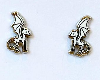 May include: A pair of silver earrings featuring a white skeletal winged horse design.