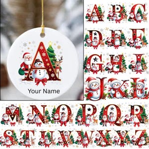 Puede incluir: Adorno navideño de cerámica blanca con una cuerda dorada, con la letra "A" en rojo con ilustraciones festivas de Papá Noel, un muñeco de nieve, un árbol de Navidad y un reno. El texto "Your Name" está debajo.