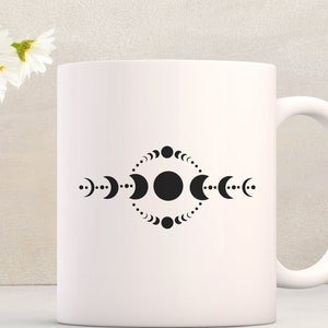 May include: White ceramic mug with a black design of a circle surrounded by a ring of crescent moons and dots.