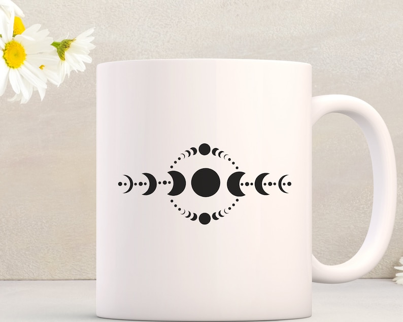 May include: White ceramic mug with a black design of a circle surrounded by a ring of crescent moons and dots.