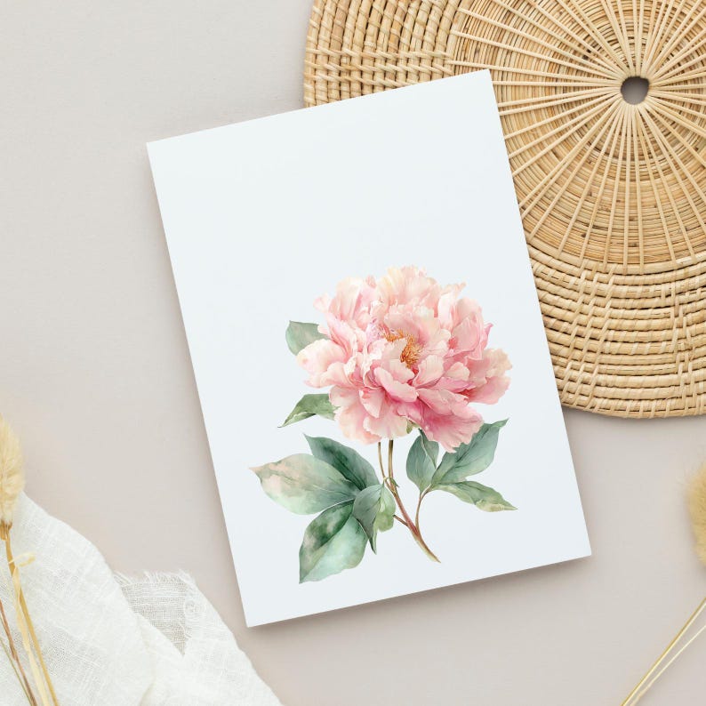 Puede incluir: Una tarjeta blanca con una ilustraci&oacute;n de acuarela de una flor de peon&iacute;a rosa y hojas verdes. La flor tiene m&uacute;ltiples capas de p&eacute;talos rosas suaves y un centro amarillo. La tarjeta est&aacute; sobre un fondo neutro con una cesta de mimbre.