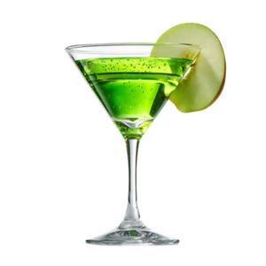 May include: A green cocktail in a martini glass, garnished with a green apple slice. The drink has a vibrant green colour and is set against a white background. The glass has a long stem and a wide rim.