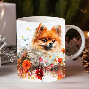 May include: White ceramic mug with a watercolor illustration of an orange Pomeranian dog surrounded by colorful flowers. The dog is looking directly at the viewer.