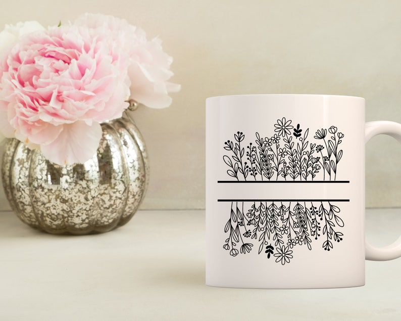 May include: White ceramic mug with a black line design of flowers and leaves. The flowers are upside down on the bottom half of the mug.