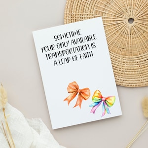 May include: A white card with the text "Sometime your only available transportation is a leap of faith."  Two watercolour bows are on the card, one orange and one rainbow.