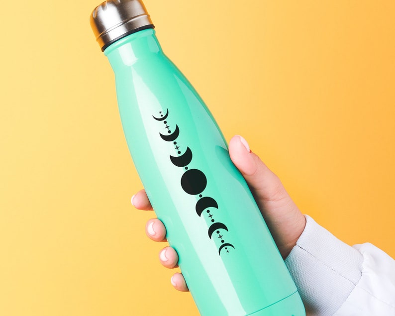 May include: A turquoise reusable water bottle with a black and white moon phase design. The bottle has a silver lid.