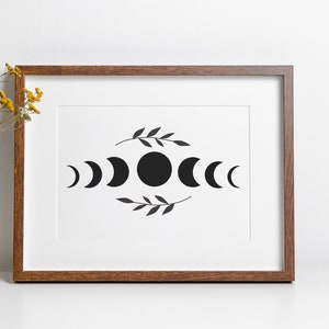 May include: A framed print with a black and white illustration of the phases of the moon with a simple leaf design above and below the moon phases.