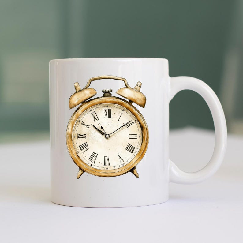 May include: A white ceramic mug with a gold alarm clock illustration. The clock face has Roman numerals and black hands.