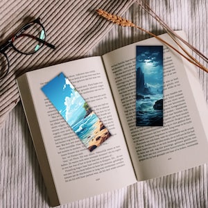 May include: Two bookmarks with painted scenes. One bookmark features a beach scene with a blue sky, white clouds, and a sandy beach. The other bookmark features a dark blue ocean scene with a moon and a rocky island.