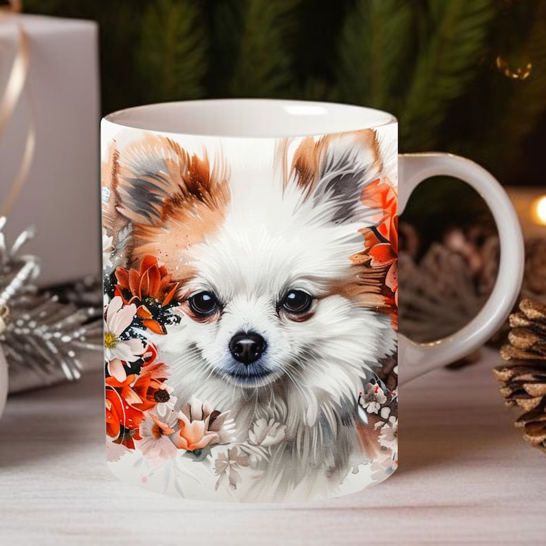 May include: White ceramic mug with a colorful illustration of a small white dog with brown fur around its ears and eyes. The dog is surrounded by orange, red, and white flowers.