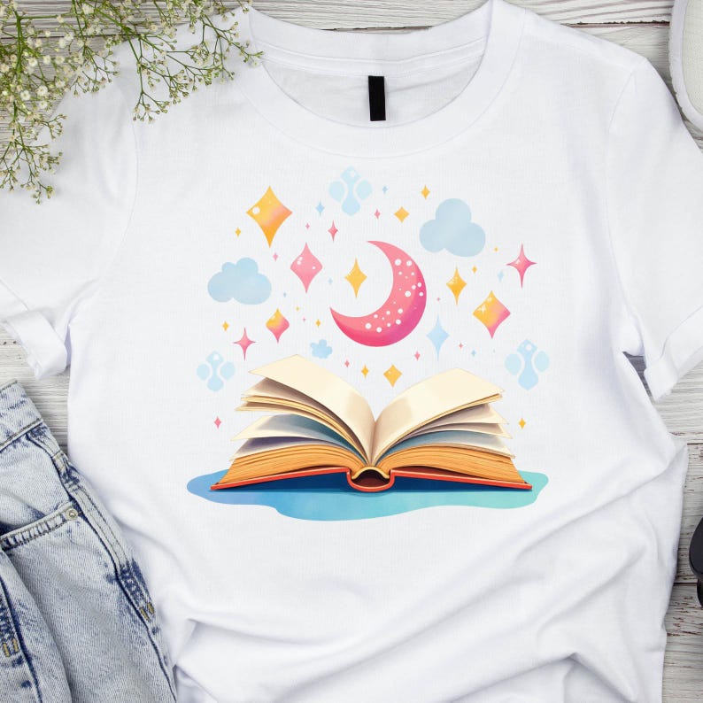 K&ouml;nnte beinhalten: Wei&szlig;es T-Shirt mit einer farbenfrohen Illustration eines offenen Buches, eines Halbmonds, Sternen und Wolken. Das Design verwendet Rosa, Orange, Gelb und Blau. Das T-Shirt besteht aus einem weichen, bequemen Material.