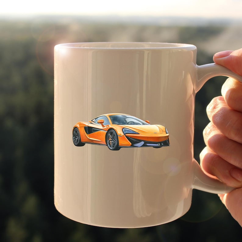 May include: A white ceramic mug featuring an orange sports car design. The car is a vibrant orange with black and silver accents. The mug has a standard handle and a smooth, glossy finish. The background is blurred, suggesting an outdoor setting.