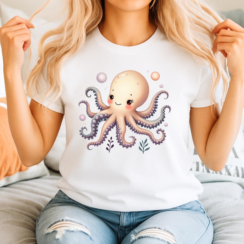 May include: White t-shirt featuring a cartoon octopus with a smiling face, pink cheeks, and purple tentacles. The octopus is surrounded by bubbles and small plant illustrations. The shirt is made of a soft material.