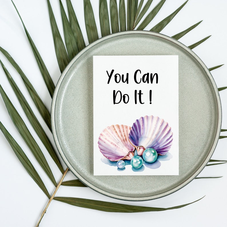 May include: A white card with the text "You Can Do It!" in black lettering. The card features a watercolor illustration of two seashells with pearls.