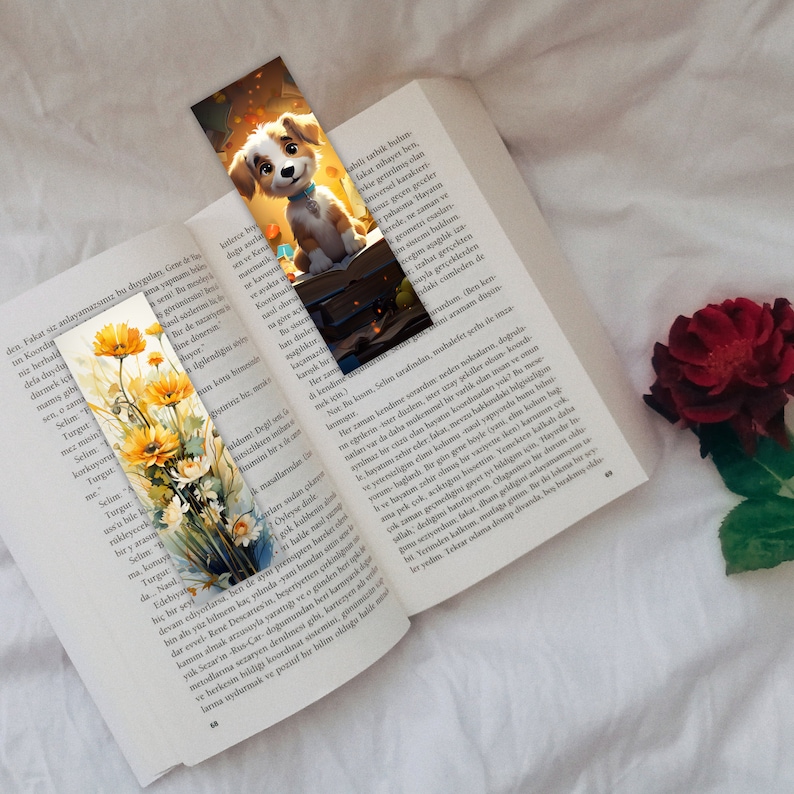 May include: A bookmark featuring a cartoon dog with brown fur, a white chest, and brown eyes. The dog is sitting on a stack of books with a yellow and orange glow behind it. The bookmark is placed on a book with text in a foreign language.