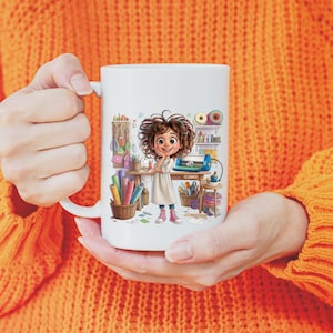 May include: A white ceramic mug featuring a colourful cartoon illustration of a person with curly brown hair standing in a craft room. The scene includes a wooden desk, a cutting machine, shelves with yarn, and baskets filled with various craft supplies.