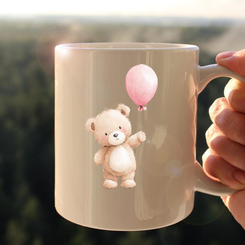 Puede incluir: Taza de cer&aacute;mica beige con una ilustraci&oacute;n de acuarela de un oso de peluche sosteniendo un globo rosa. El oso tiene pelaje marr&oacute;n claro y una barriga blanca. El globo es redondo y rosa.