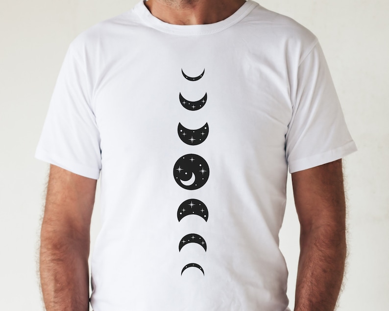 May include: White t-shirt with a black graphic of the moon phases. The moon phases are in a vertical line, starting with a crescent moon and ending with a full moon.