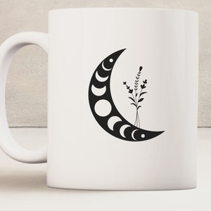 May include: White ceramic mug with a black crescent moon design featuring phases of the moon and a small black floral design.