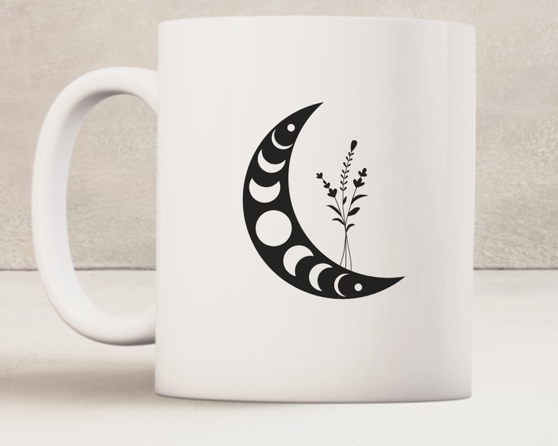 May include: White ceramic mug with a black crescent moon design featuring phases of the moon and a small black floral design.