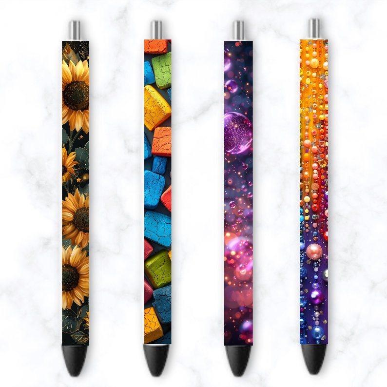 May include: Four pens with different colorful designs. The first pen has a sunflower pattern, the second has a colorful block pattern, the third has a purple and pink galaxy pattern, and the fourth has a rainbow bead pattern.