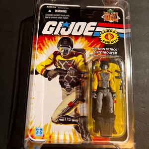 May include: A G.I. Joe Python Patrol Elite Trooper action figure in its original packaging. The figure is dressed in yellow and gray uniform. The packaging features the G.I. Joe logo and the Cobra Enemy emblem.