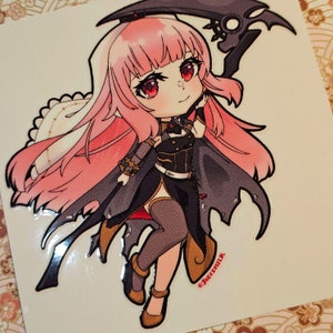May include: A sticker featuring a cartoon illustration of a pink-haired girl in a black and gold outfit holding a black scythe. The girl has red eyes and a red bow in her hair. The sticker has a glossy finish and is signed "Jademilk".