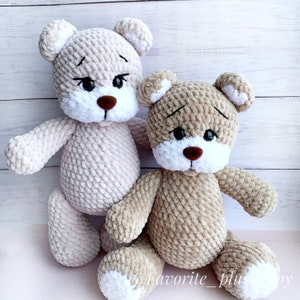 May include: Two crocheted teddy bears, one in a light beige color and the other in a darker beige color. Both bears have white faces with black eyes and brown noses.