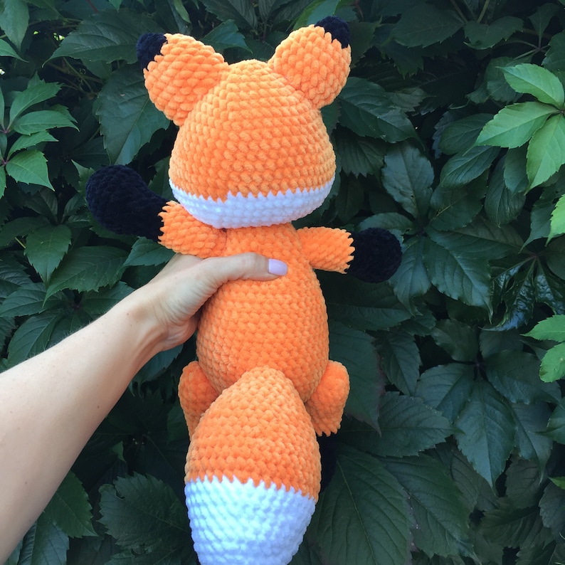 Op de afbeelding: Een gehaakt oranje pluche vosje met zwarte ogen en een witte staartpunt.