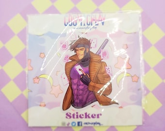 May include: A sticker featuring a cartoon illustration of Gambit from the X-Men. He is wearing a purple shirt, brown jacket, and holding a playing card. The background is a pastel blue with stars and clouds. The sticker says "Sticker" and "Cosplay Shop" in the bottom right corner.