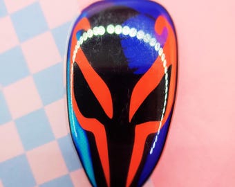 May include: A black, red, and blue alien mask with a white outline. The mask is made of resin and has a glossy finish.