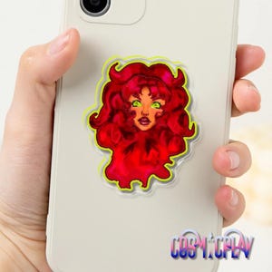May include: A phone grip featuring a vibrant illustration of a character with fiery red hair and green eyes. The artwork is outlined in neon green and is affixed to a smartphone. The text "COSYTOPLAY" is visible at the bottom.