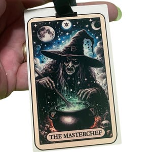 May include: A rectangular card depicting a witch stirring a green potion in a cauldron. The witch is wearing a black hat, set against a starry night sky with a full moon. The text "THE MASTERCHEF" is at the bottom.