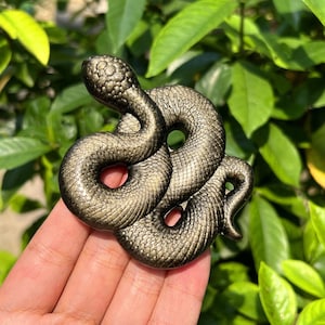 Peut inclure: Une figurine de serpent en métal de couleur dorée avec une surface texturée détaillée. Le serpent est enroulé en forme de spirale.