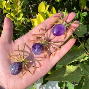 May include: Three gold spider sculptures with amethyst gemstone bodies. Each spider has eight legs and a round body.