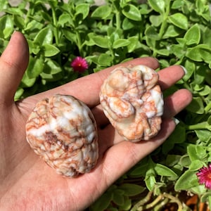 May include: Two white and red striped heart-shaped stones. The stones have a natural, rough texture.