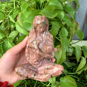 May include: A hand-carved pink and green stone sculpture of a mother and child. The sculpture is made of a type of stone that has a speckled appearance.