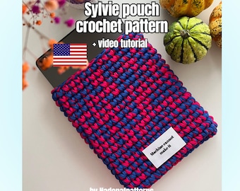 Peut inclure: Une pochette rectangulaire au crochet avec un motif de fil panaché bleu et rose vif. Une étiquette rectangulaire blanche est cousue sur le devant avec le texte noir Machine cannot make it. Le texte Sylvie pouch crochet pattern + video tutorial est visible au-dessus de la pochette, avec une petite icône de drapeau des États-Unis et le texte by Nadenafpatterns.
