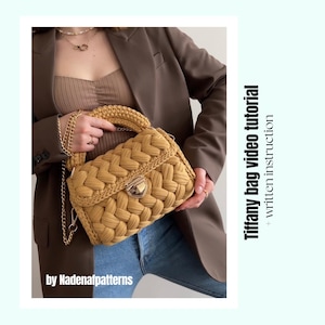 Puede incluir: Un bolso de ganchillo color amarillo mostaza con una textura trenzada gruesa, un cierre de metal dorado y una correa de cadena dorada a juego. El texto Tiffany bag video tutorial + written instruction by Nadenafpatterns es visible.