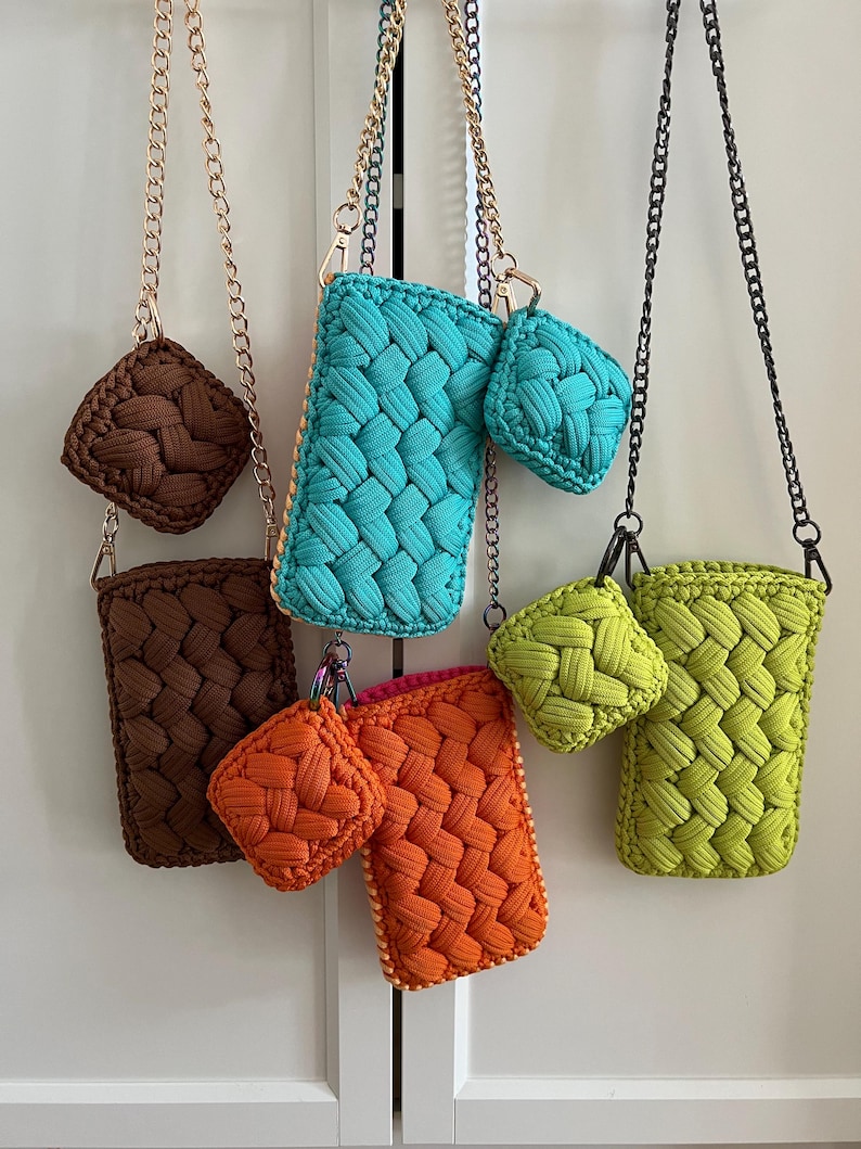 May include: A collection of rectangular crochet pouches and matching square coin purses in brown, turquoise, orange, and lime green. Each item features a woven cord texture and is attached to a metallic chain strap with a lobster clasp.