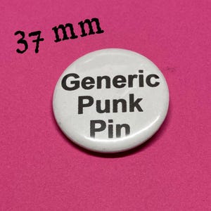May include: A white, round button pin with the text "Generic Punk Pin" in black, set against a pink background. The pin measures 37 mm in diameter.