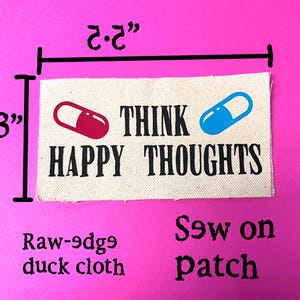 May include: A rectangular, raw-edge duck cloth patch that is 3 inches tall and 2.2 inches wide. The patch features the words "THINK HAPPY THOUGHTS" in black, with a red and a blue capsule graphic. The patch is designed to be sewn on.