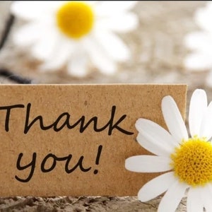 May include: A brown paper tag with the text "Thank you!" written in black ink. The tag is tied with black twine and surrounded by white daisies with yellow centres.