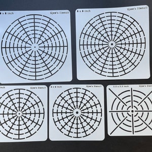 May include: Set of five white plastic stencils with circular designs. The stencils are 8 inches, 6 inches, and 5.5 inches in diameter. Each stencil features a different pattern of concentric circles and lines.