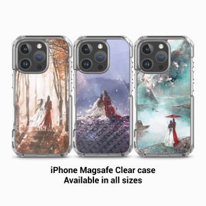 May include: Three clear phone cases with different designs. The first case features a watercolour painting of two figures in a forest. The second case features a watercolour painting of two figures on a mountaintop. The third case features a watercolour painting of two figures by a lake. The text "iPhone Magsafe Clear case Available in all sizes" is below the cases.