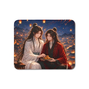May include: A rectangular mouse pad featuring an illustration of two individuals with long dark hair in traditional robes, one in white and one in red, sharing small round cakes on a plate against a backdrop of a night sky filled with glowing lanterns.