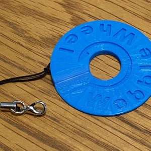 May include: A blue plastic keyring with a ring and a black cord. The keyring has the words "Whale World" written on it.