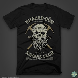 Puede incluir: Camiseta negra con un gráfico dorado de una calavera con barba y picos cruzados. El texto "KHAZAD-DUM -DWARROWDELF- 29 89 AZANULBIZAR MINERS CLUB" está impreso en la camiseta.