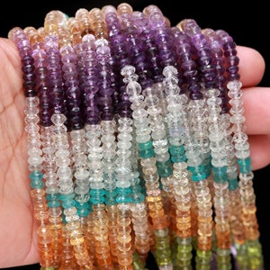May include: Multiple strands of faceted rondelle beads in a gradient of colors including deep purple, light purple, clear, teal, orange, and light green. The small, circular, translucent gemstone beads are strung together in vertical rows.