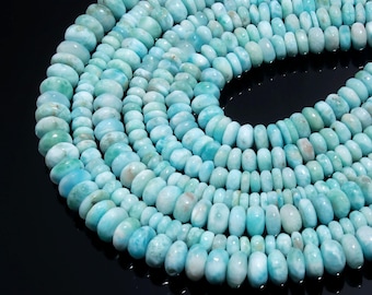 May include: A strand of round, flat, disc-shaped Larimar beads in varying shades of light blue, turquoise, and white. The beads are arranged in a circular pattern, showcasing their smooth, polished surfaces and natural marbled color variations.